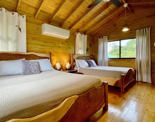 a bedroom with two beds in a log cabin at Finca Los Mangos in Manuel Antonio