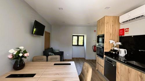 een woonkamer met een houten tafel en een keuken bij A Casa do Penedo - Arcos de Valdevez in Arcos de Valdevez