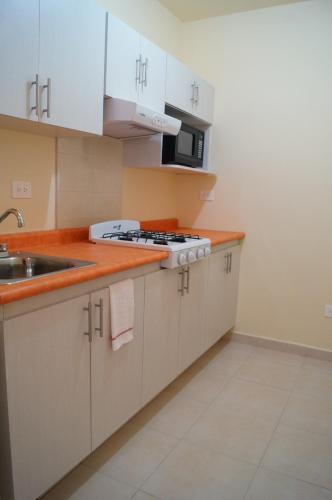 a kitchen with white cabinets and a sink at MV Suites in Monterrey