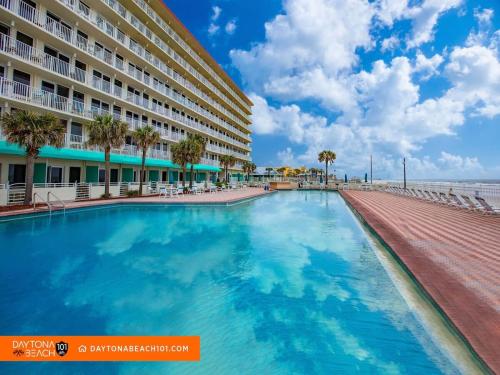 a swimming pool in front of a hotel and the beach at Amazing Studio Steps Away From The Atlantic Ocean! in Daytona Beach