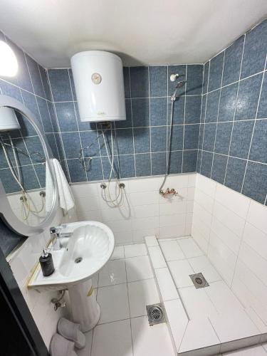 a blue tiled bathroom with a sink and a shower at Hostel 8 in Prishtinë