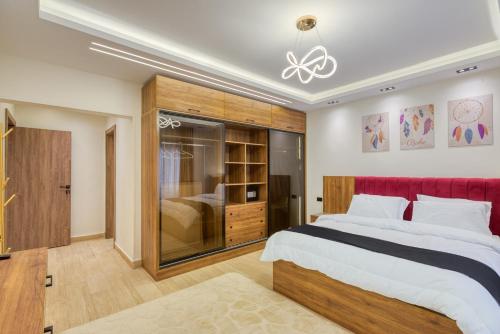 a bedroom with a large bed with a red headboard at Luxurious 3Bd Hotel Apt in compound Sheikh Zayed with Pool and Gym access in Sheikh Zayed