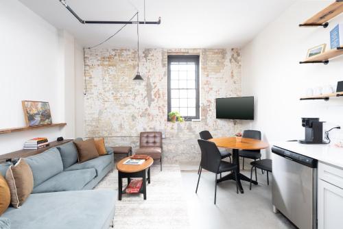 Brewery District 2-Story 2BR Apt Near Fiserv with Rooftop, Gym, and Parking في ميلووكي: غرفة معيشة مع أريكة وطاولة