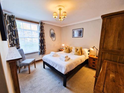 a bedroom with a bed and a chair and a window at Hartwood Cottage - 33 Longwestgate in Scarborough
