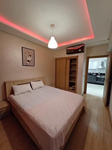 a bedroom with a large bed with a light on the ceiling at Apartment kamal park E21 in Mohammedia