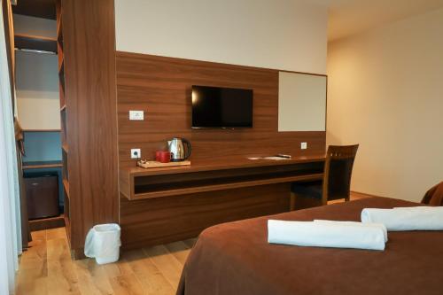 a hotel room with a bed and a desk with a television at Hotel Semitronix in Peje