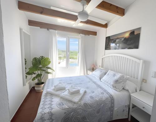 Una habitación blanca con una cama y una ventana en Costa Arenal 52, en Arenal d'en Castell