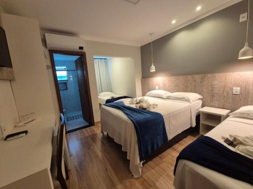 a hotel room with two beds and a hallway at Pousada Vale do Chapéu in Capitólio