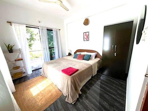 a bedroom with a bed and a large window at Casa Palolem in Canacona