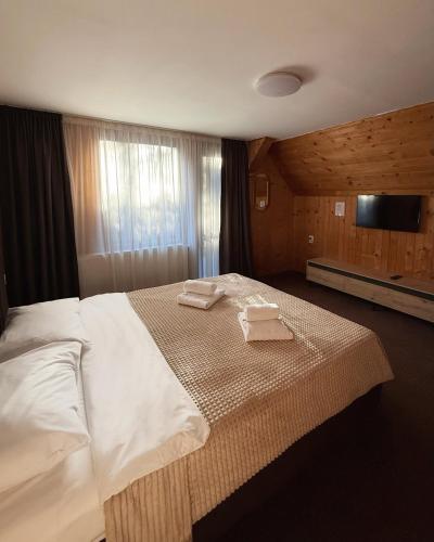a bedroom with a large bed with two towels on it at Vila Casa Familiei Poiana Braşov in Poiana Brasov