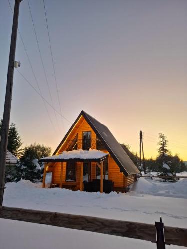 a wooden cabin with snow on the roof at Evergreen cabins Golija in Golija