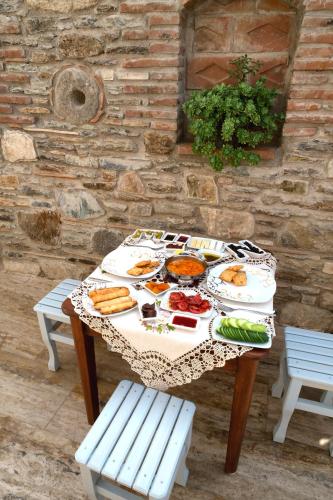 a table with plates of food on it with two benches at Hotel Mary's House in Selcuk