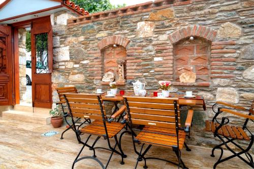 a wooden table and chairs in front of a stone wall at Hotel Mary's House in Selcuk