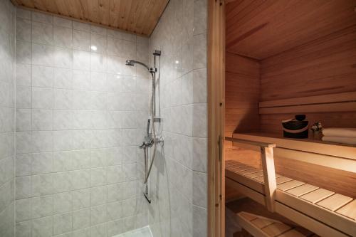 a shower in a sauna with a wooden ceiling at White Elegant Suite by the River in Rovaniemi