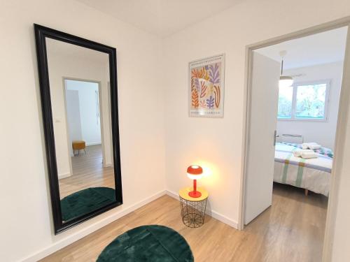 L'Art Pop - Chic & Coloré Plage à 5 min en voiture في Biville-sur-Mer: مرآة في غرفة مع سرير ومصباح