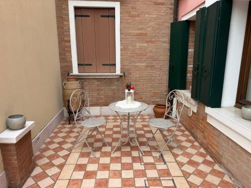 a patio with a table and two chairs and a window at Ca' Dolce Rosa in Burano