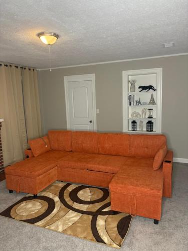 8mins from Jaguar stadium & the Historical Riverside في جاكسونفيل: غرفة معيشة مع أريكة بنية وسجادة