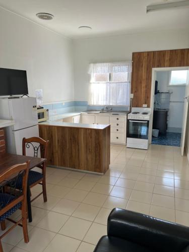 a large kitchen with white appliances and a table and chairs at Restawile Motel in Busselton