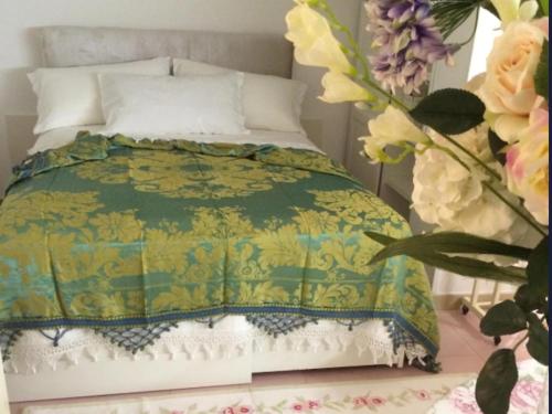 a bed with a green and yellow comforter and flowers at La Roseraie in Battipaglia