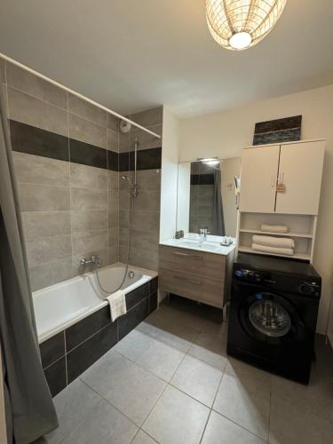 a bathroom with a tub and a washing machine at Appartement cosy et confortable à deux pas du lac in Excénevex