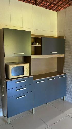 a kitchen with a blue counter with a microwave at Casa em Porto de pedras in Tatuamunha