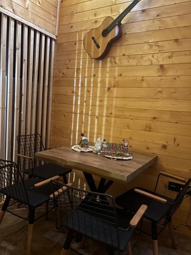 a wooden table with chairs and a guitar on a wall at Driftwood Dreams in Cetinje