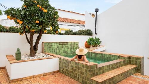 a woman in a hat sitting in a swimming pool in a house at Casa da Sé Renovated Traditional Townhouse with Courtyard in Silves