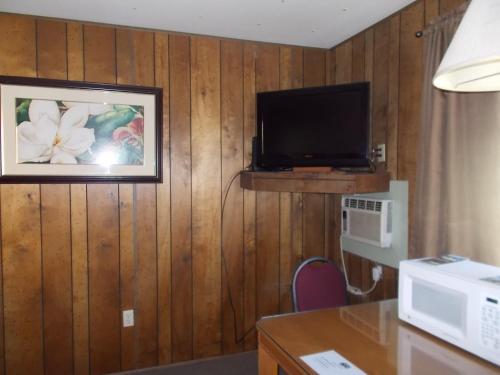a room with a tv on a wall with wood paneling at Atomic Inn Beatty Near Death Valley in Beatty
