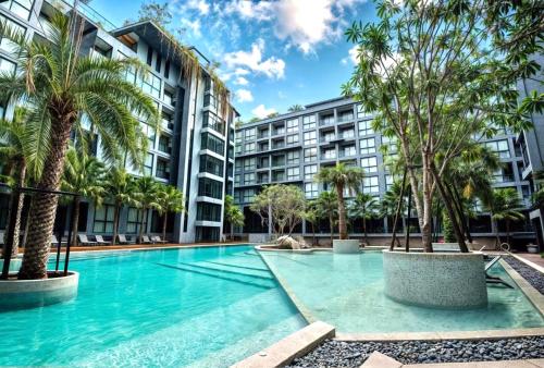 a swimming pool with palm trees and buildings at The Kamala View in Kamala Beach