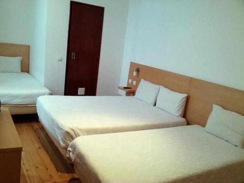 a hotel room with two beds and a door at Internacional in Coimbra