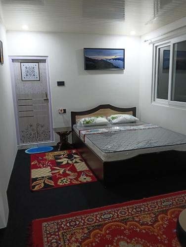 a bedroom with a bed and a door and a rug at Wind chimes villa in Karsiyang