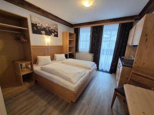 a bedroom with a large bed with white sheets at Apparthotel Kirchgasser in Obertauern
