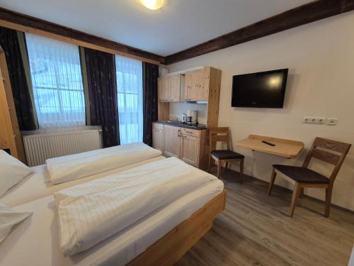 a bedroom with a bed and a desk and a television at Apparthotel Kirchgasser in Obertauern