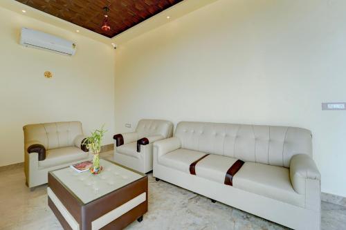 a living room with two white couches and a table at Hotel O ESTORIA HOTEL & RESORT in Kadakola