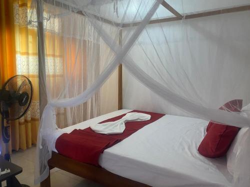 a bedroom with a canopy bed with red and white sheets at Sedasi Holiday Home in Tangalle