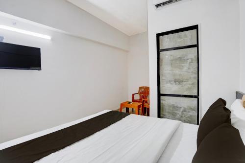ein Schlafzimmer mit einem Bett und einem Fernseher an der Wand in der Unterkunft Hotel O Sai Shlok Inn Lodging in Nashik