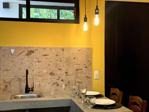 een keuken met een wastafel en een tafel met wijnglazen bij 1-Bed Loft in Oaxaca - Steps from Downtown in Oaxaca City