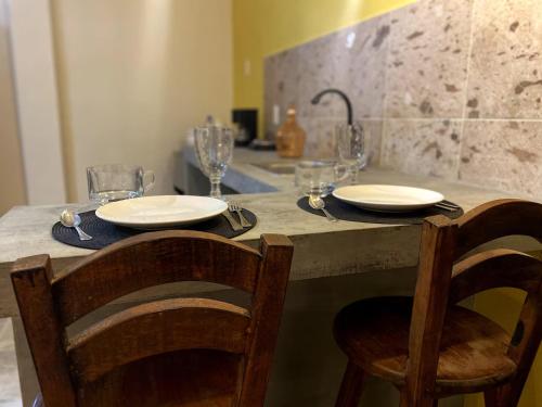 een tafel met twee stoelen en borden en glazen erop bij 1-Bed Loft in Oaxaca - Steps from Downtown in Oaxaca City