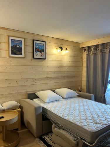 LE CORBIER Vue pistes Studio 5 personnes entièrement rénové في Villarembert: غرفة نوم بها سرير في جدار خشبي