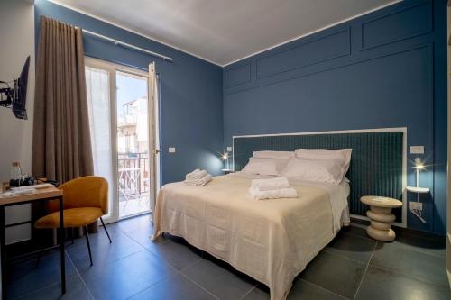 a blue bedroom with a bed and a desk and a window at Dimora Fortunato in Bernalda
