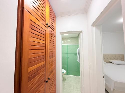 a bathroom with a wooden door next to a sink at Flat estudio 110 Amarilis Riviera de São Lourenço, 03 piscina climatizada, serviço de hotelaria, limpesa e troca de toalhas diária, carregador veiculo elétrico e servico de praia finais de semana WiFi 500 in Riviera de São Lourenço