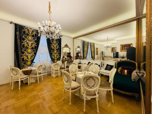 a dining room with white chairs and tables and a chandelier at Conacul Coroanei Luxury Boutique Hotel in Bucharest