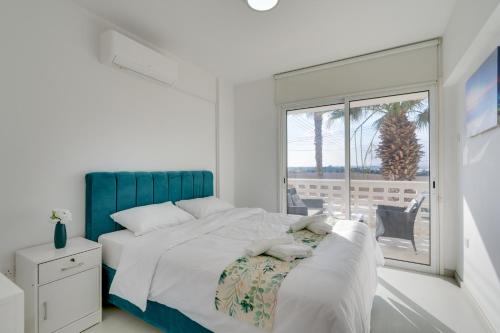 ein weißes Schlafzimmer mit einem großen Bett und einem Fenster in der Unterkunft Elisabeth Salt Lake views 200m from Makenzy beach in Larnaka