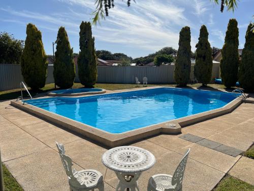 a swimming pool in a yard with chairs and trees at Restawile Motel in Busselton