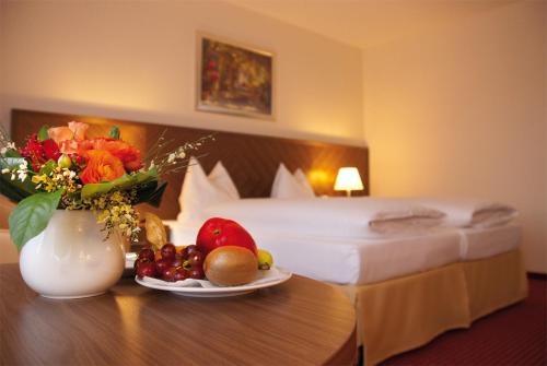 a hotel room with a bed and a table with a plate of fruit at Morada Hotel Gifhorn in Gifhorn
