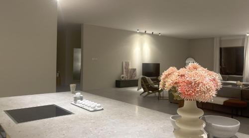 a living room with a vase with flowers on a table at Al Ain Farm Escape with Private Pool , Mini Golf , and Firepit in Bin Aḩmad