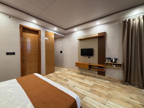 a hotel room with a bed and a flat screen tv at Muskan Mount View Retreat, Mukteshwar in Mukteswar