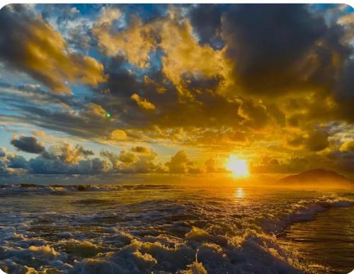 a sunset on the beach with the waves at Casa de Praia in Bertioga