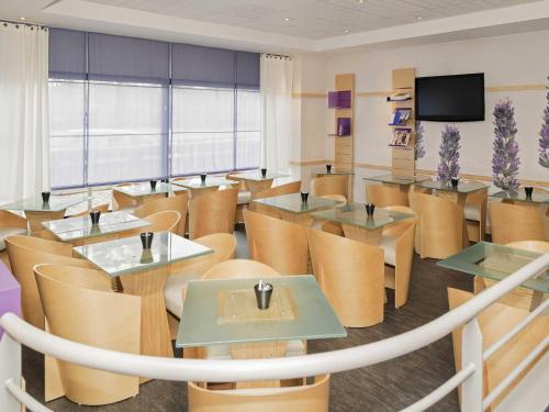 a restaurant with tables and chairs and a flat screen tv at ibis Metz Centre Gare in Metz