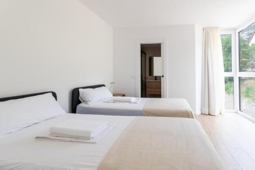 two beds in a white room with a window at Las casitas de mache - LAGOSSA in Cerler